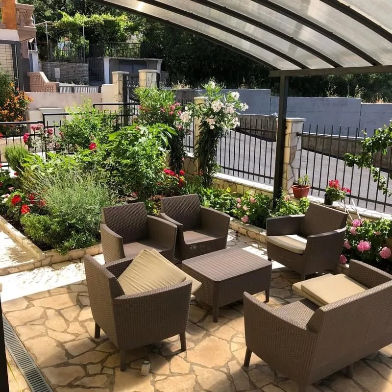 Covered terrace with patio furniture and a landscaped yard.