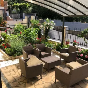Covered terrace with patio furniture and a landscaped yard. - image 4