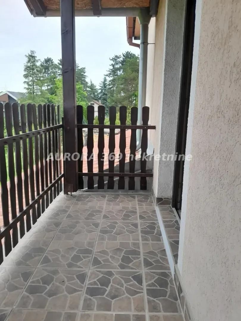 Natkriveni balkon sa drvenom ogradom i keramičkim pločicama na podu.