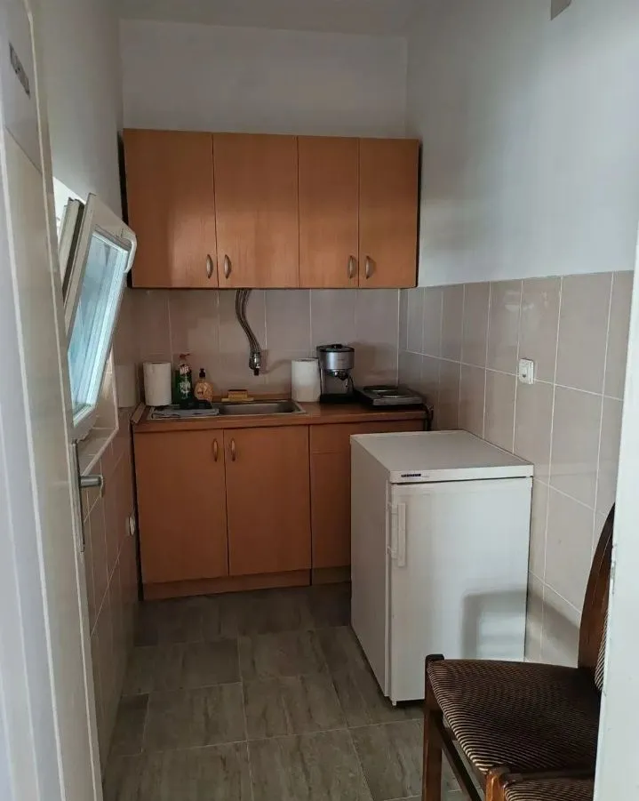 Small kitchen with wooden cabinets, sink, and a small refrigerator.