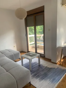 Svijetla dnevna soba sa sivom garniturom i izlazom na balkon. - image 2