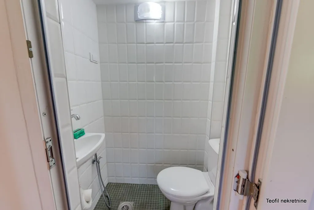 Malo kupatilo sa belim pločicama, umivaonikom i wc šoljom.
