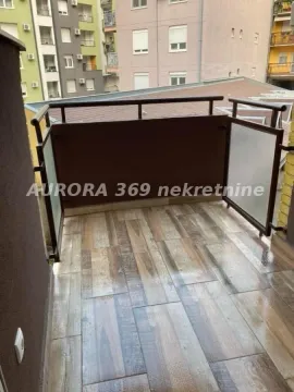 Small tiled balcony with a metal railing and a view of buildings. - image 7