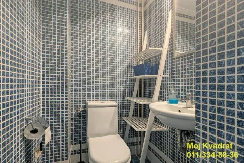 Bathroom with blue mosaic tiles, toilet, washbasin, and white shelving unit. - image 11