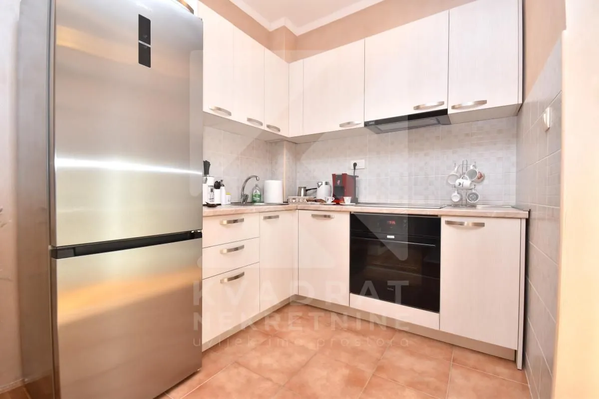 Kitchen with white cabinetry, built-in oven, and a large refrigerator.