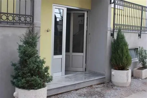 Building entrance with stairs and decorative potted plants. - image 2