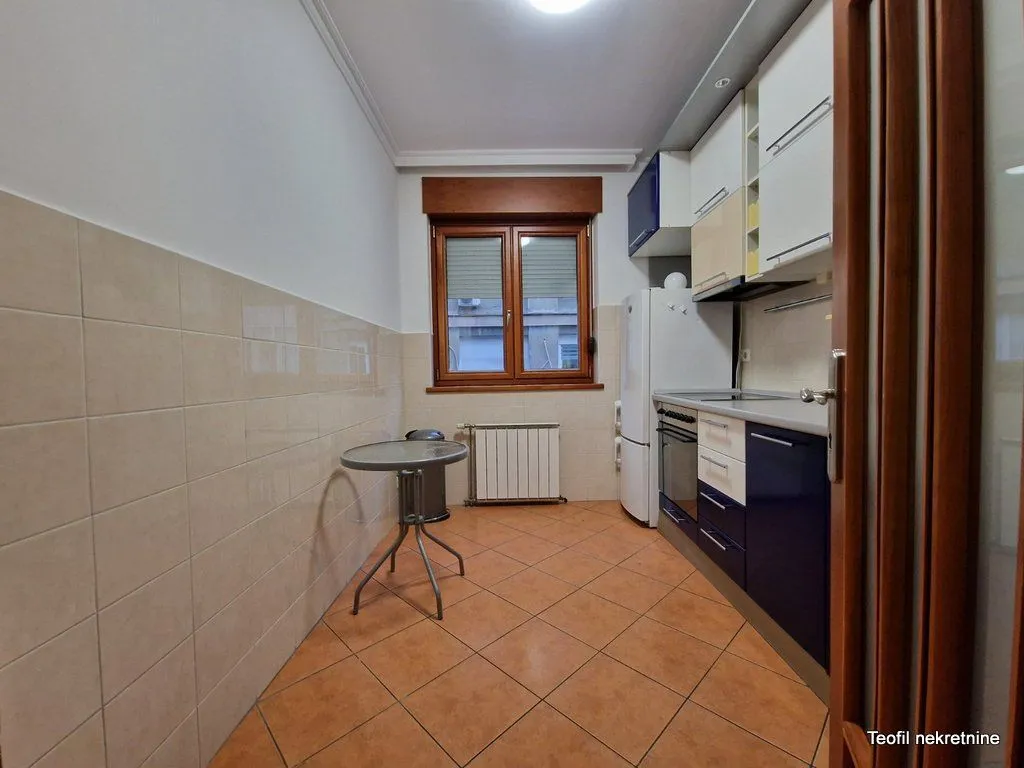 Small kitchen with cabinets and a dining table near the window.