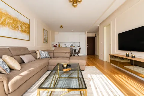 Living room with a sectional sofa, glass coffee table, and television, overlooking the kitchen. - image 17