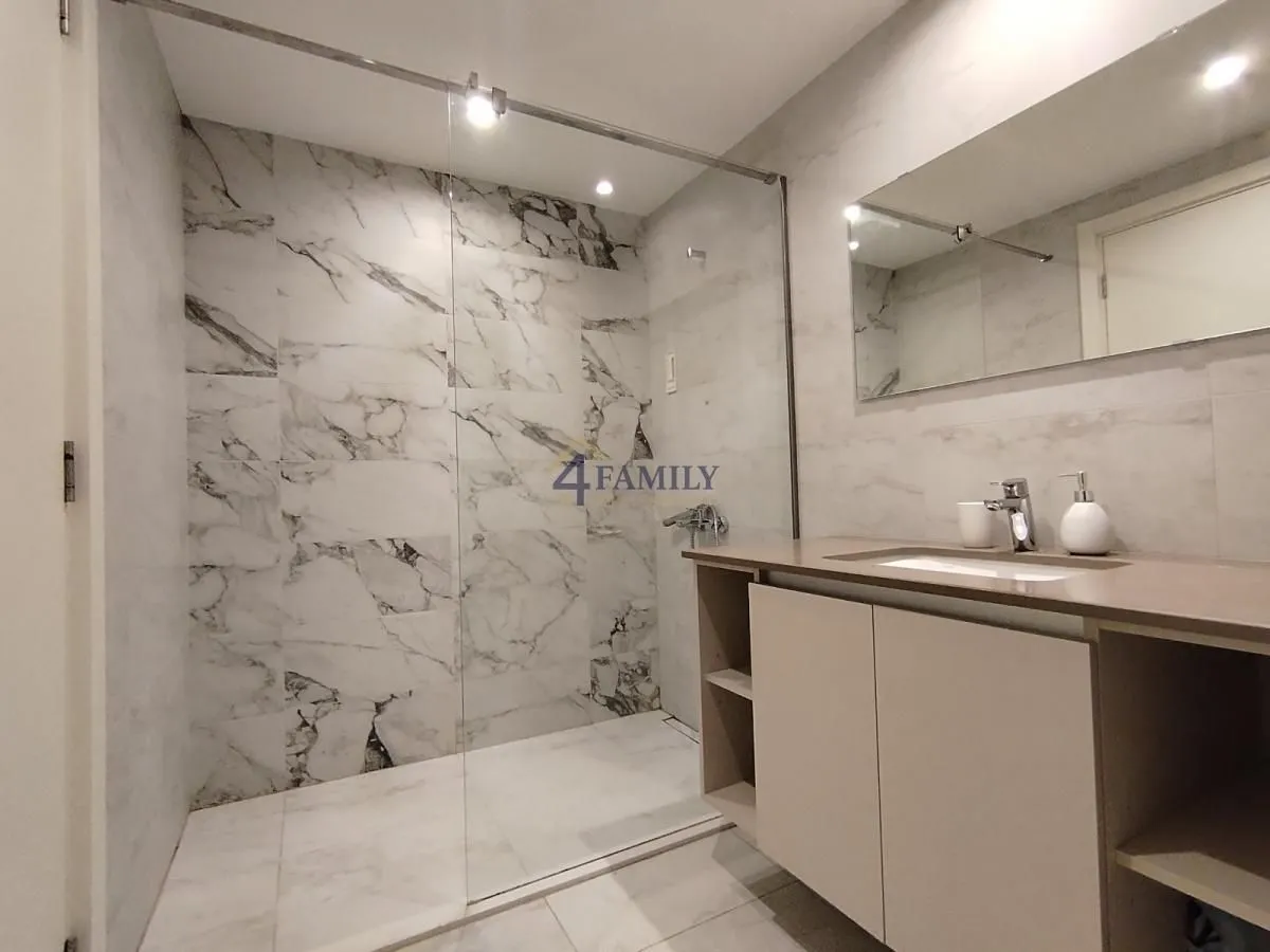 Modern bathroom with a glass-partition shower cabin and vanity sink.