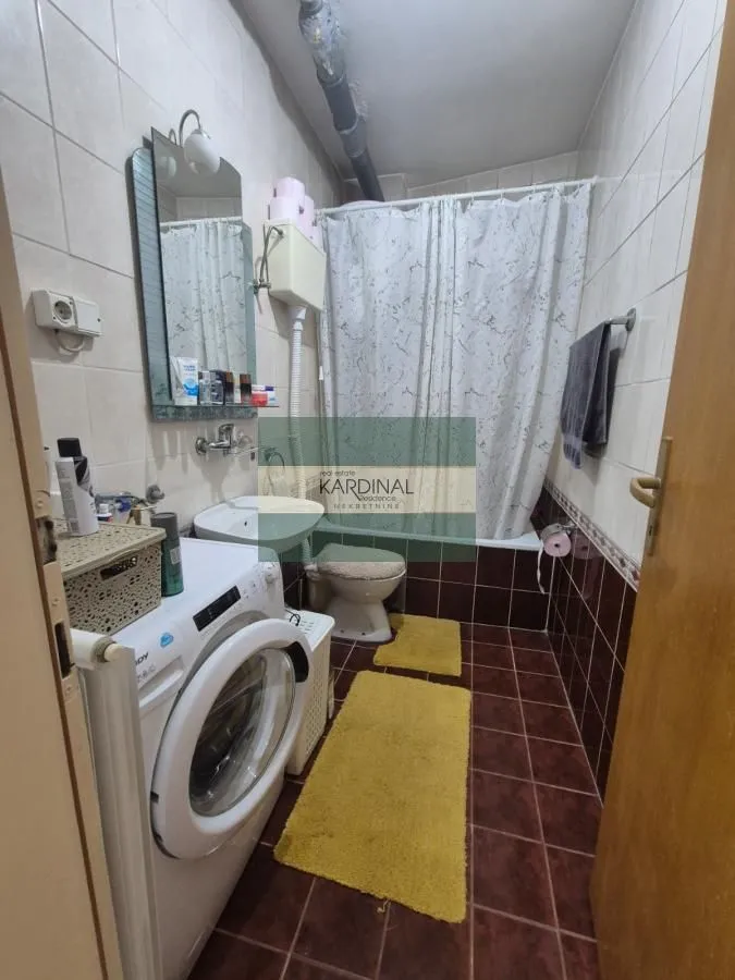Manje kupatilo sa kadom, umivaonikom, wc šoljom i veš mašinom.