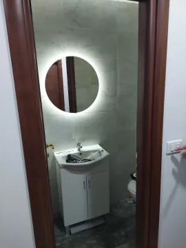 Pogled na manje kupatilo sa umivaonikom, ogledalom sa pozadinskim osvjetljenjem i toaletom. - image 7