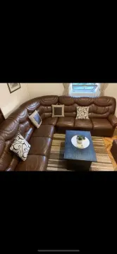Living room with a large leather sectional sofa and coffee table. - image 14