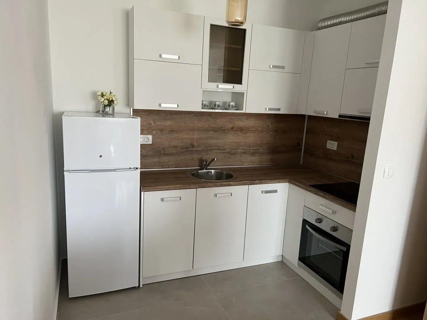 A bright kitchen with white cabinets and a wooden countertop.