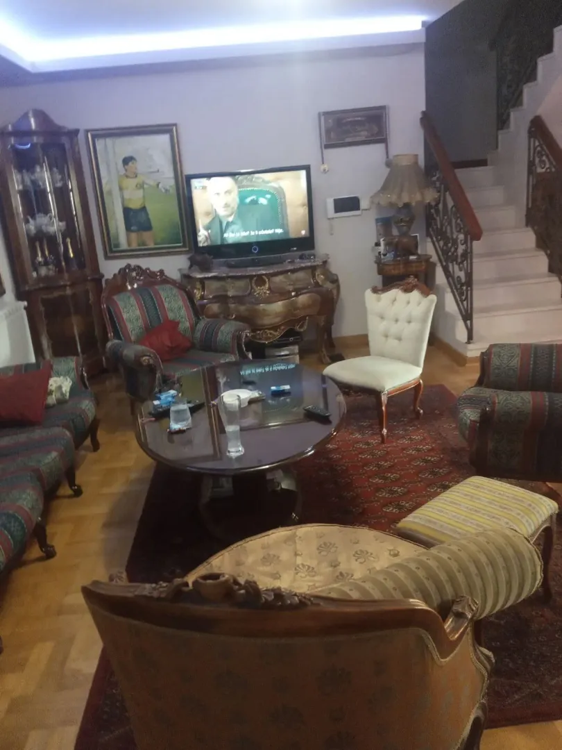 A classic-style living room featuring seating furniture, a television, and an indoor staircase.