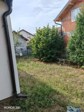Zeleno dvorište iza kuće sa drvećem i okolnim objektima. - image 17