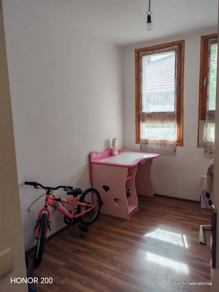 Dečja soba sa roze radnim stolom i biciklom.