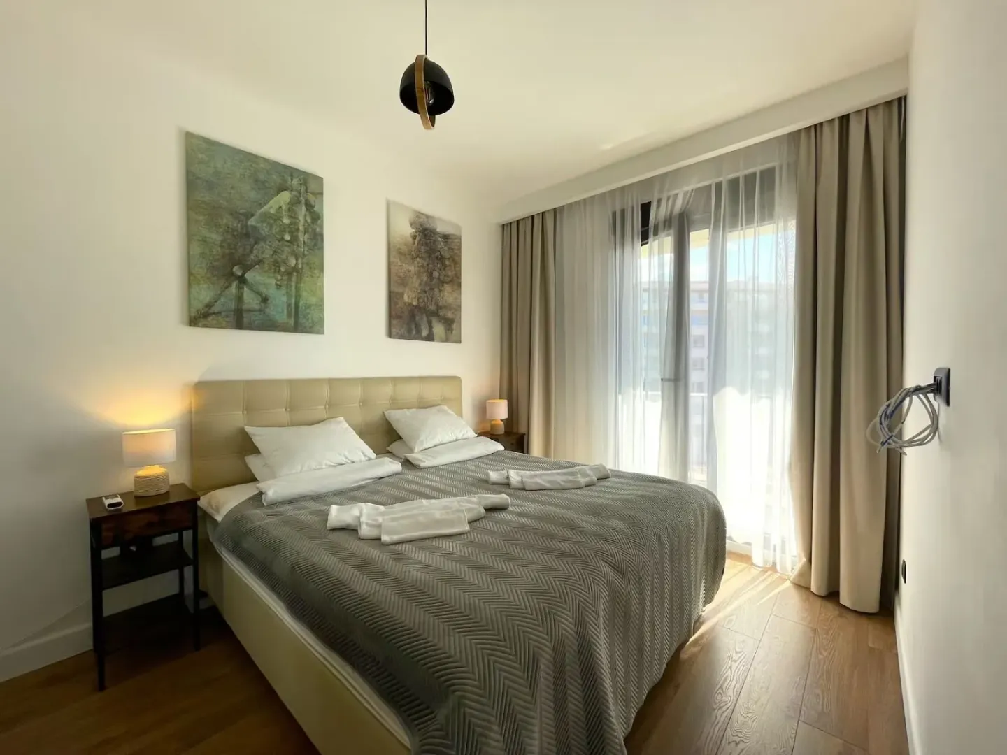Furnished bedroom with a double bed, bedside tables, and balcony doors.