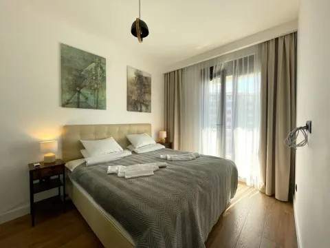 Furnished bedroom with a double bed, bedside tables, and balcony doors. - image 18