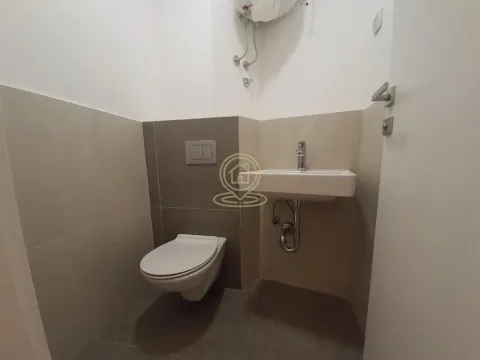 Smaller bathroom with a toilet and washbasin in light ceramic tiles. - image 6