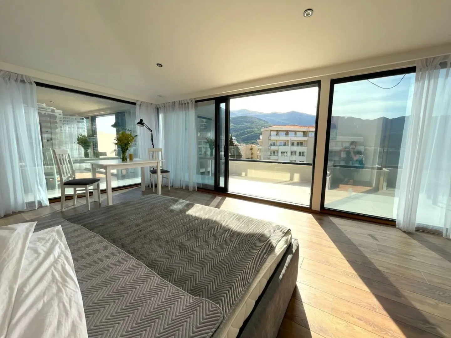 Spacious bedroom with large glass surfaces and access to a terrace with mountain views.