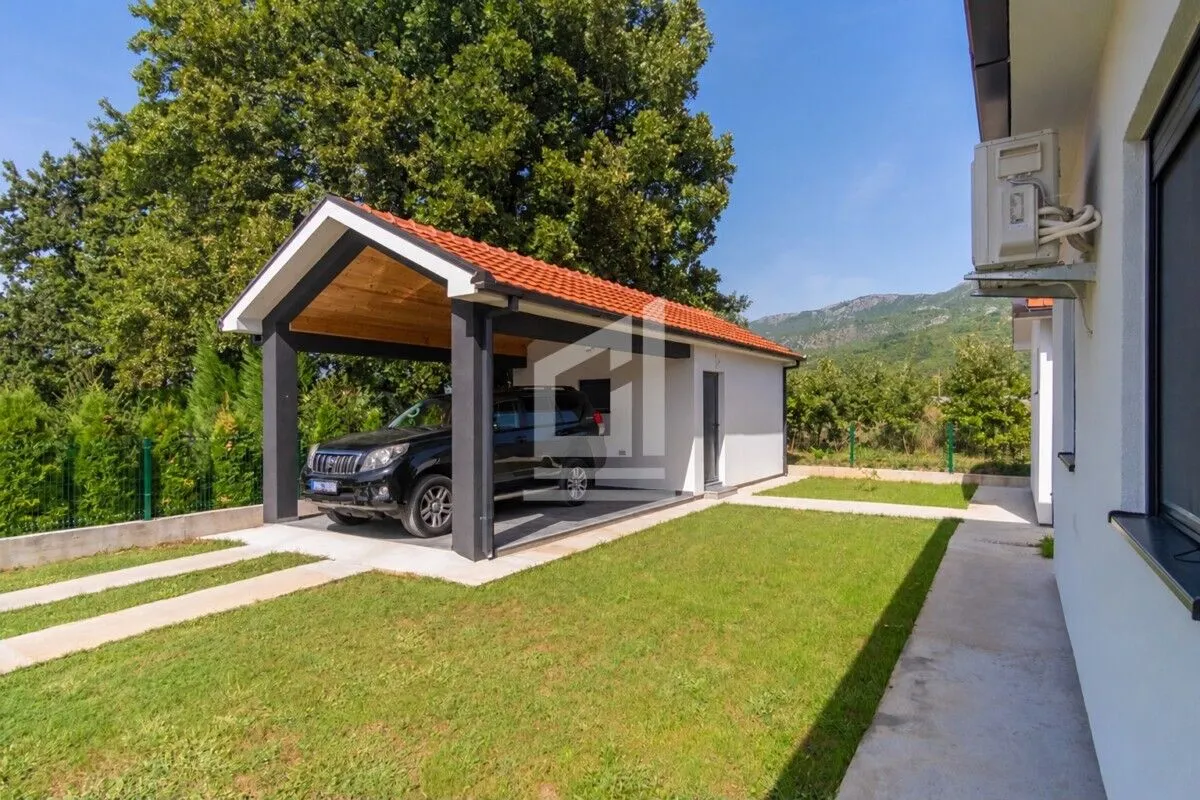 Covered parking space with a car in the yard of the house.