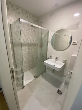 Modern bathroom with a glass shower cabin and a round mirror. - image 8