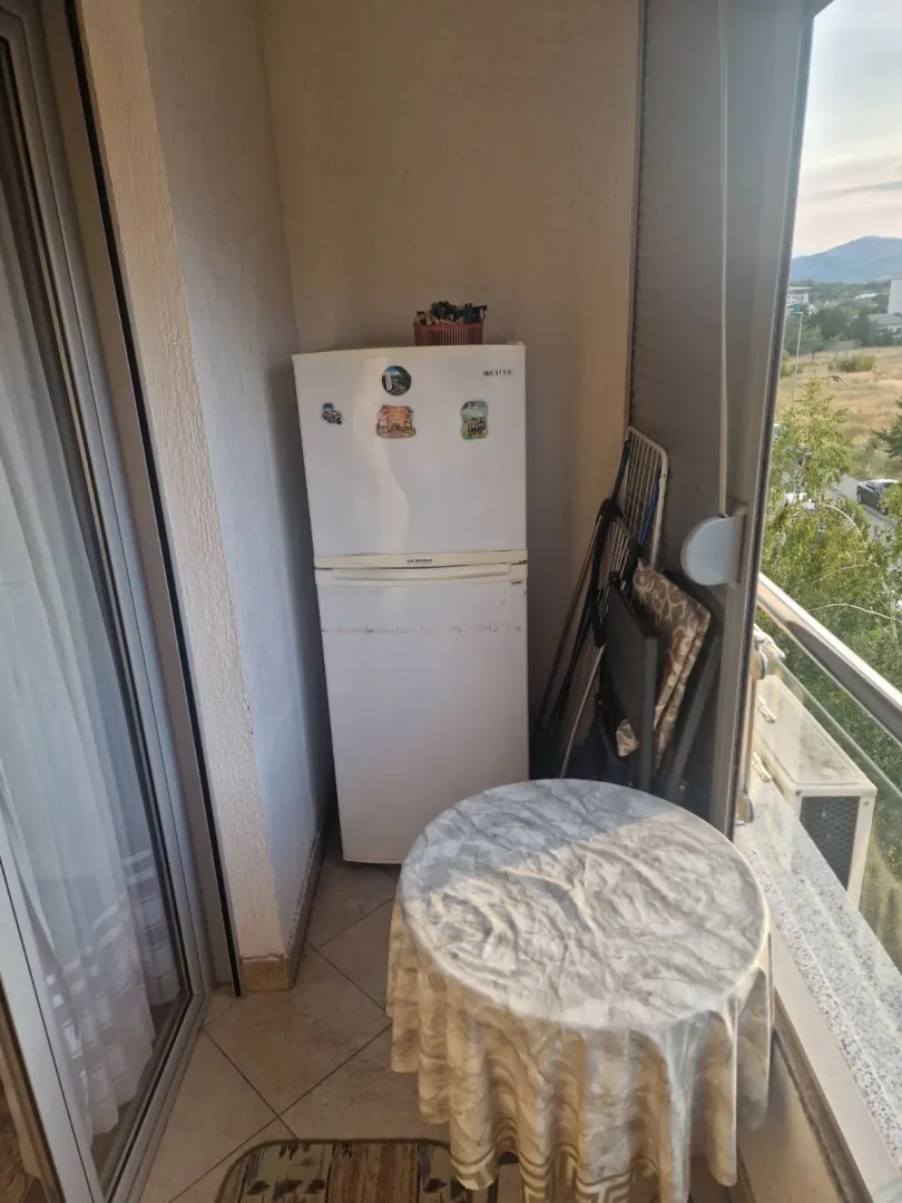 Manji zatvoreni balkon sa frižiderom, stolom i sušilicom za veš.