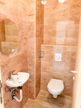 Manje kupatilo obloženo bež pločicama sa umivaonikom i wc šoljom. - image 4