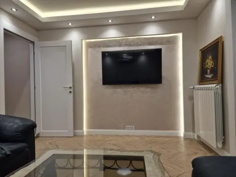 Dnevna soba sa televizorom na zidu i dekorativnom rasvetom. - image 5