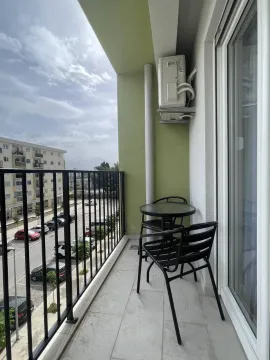 Small furnished balcony with a table, chairs, and a view of the street and parking. - image 6
