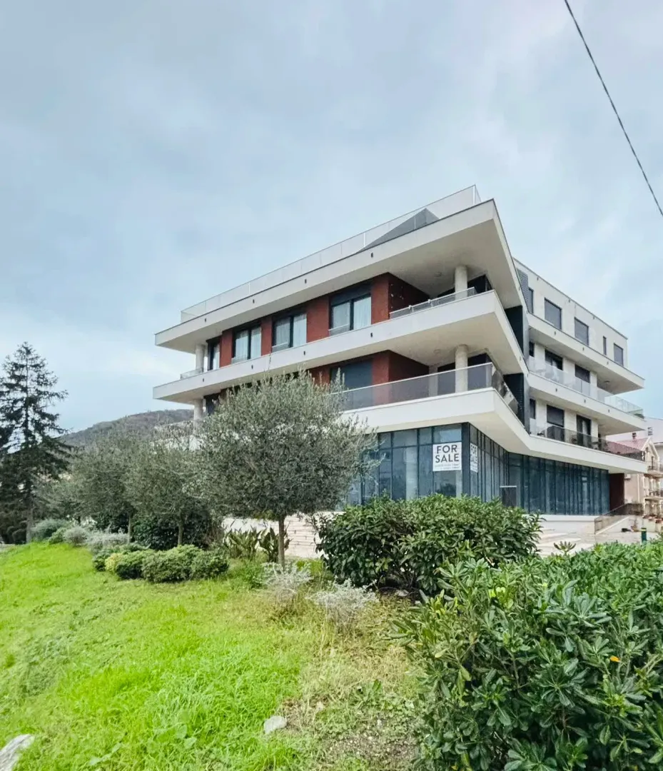 Pogled na spoljašnjost moderne stambene zgrade sa uređenim dvorištem.
