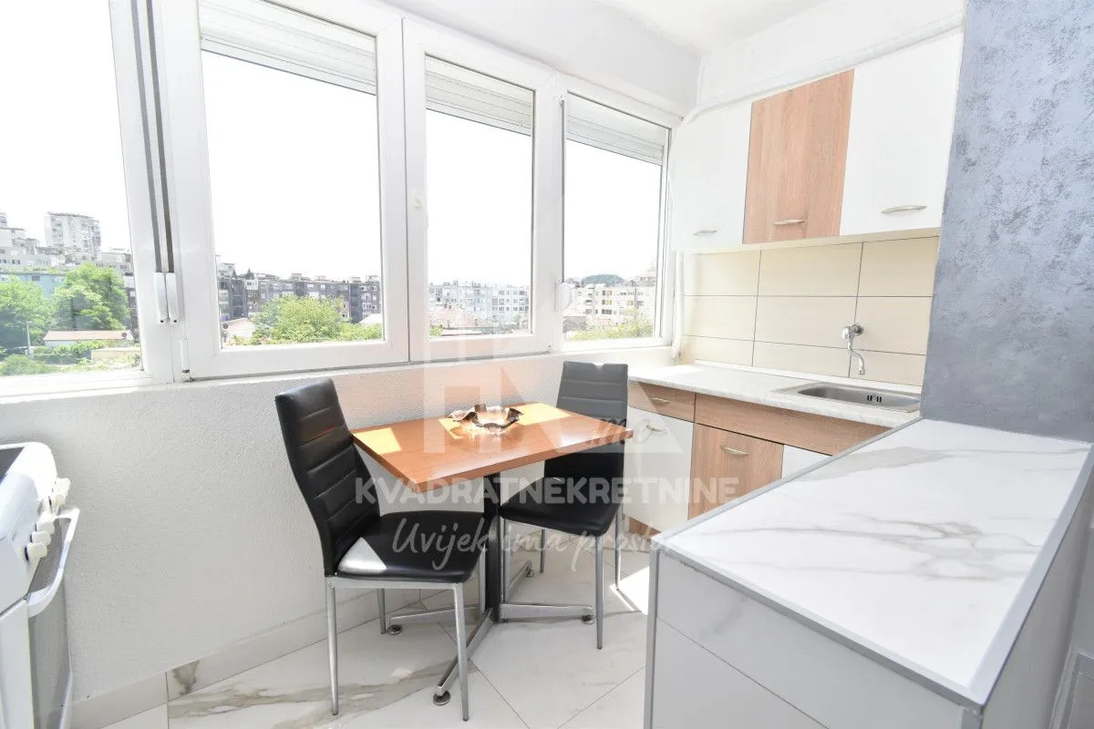 Small kitchen with a dining table and large windows overlooking the city.