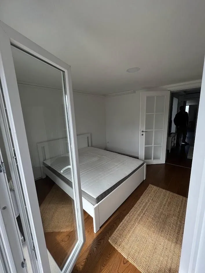 Bedroom with a white bed and wooden flooring.