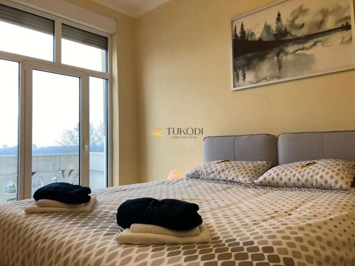 Furnished bedroom with a double bed and large balcony doors.