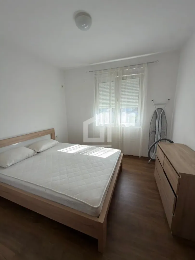 Bright bedroom with a double bed and a wooden chest of drawers.