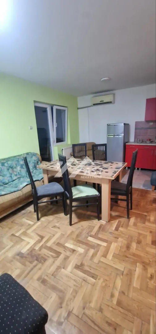 Dnevna soba sa trpezarijom i manjim kuhinjskim delom u uglu.