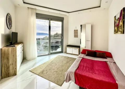 Furnished bedroom with a bed, dresser, TV, and access to a terrace with a sea view. - image 7