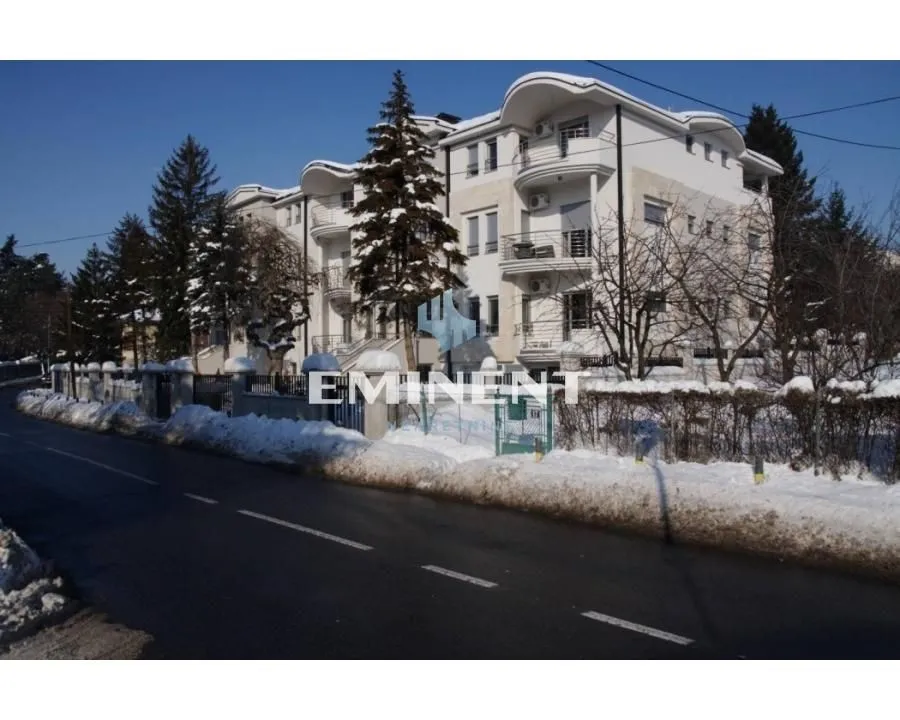 View of the exterior of the residential building with snow-covered surroundings and a street in the foreground.