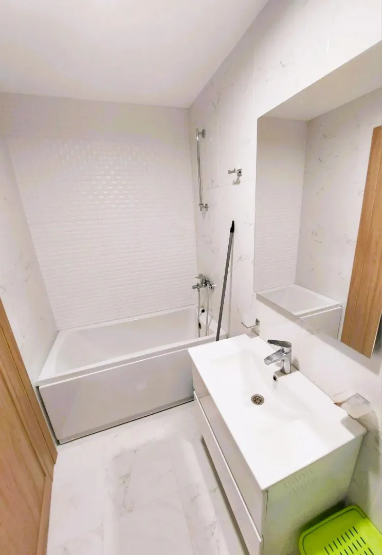 Bright bathroom equipped with a bathtub, washbasin, and mirror.