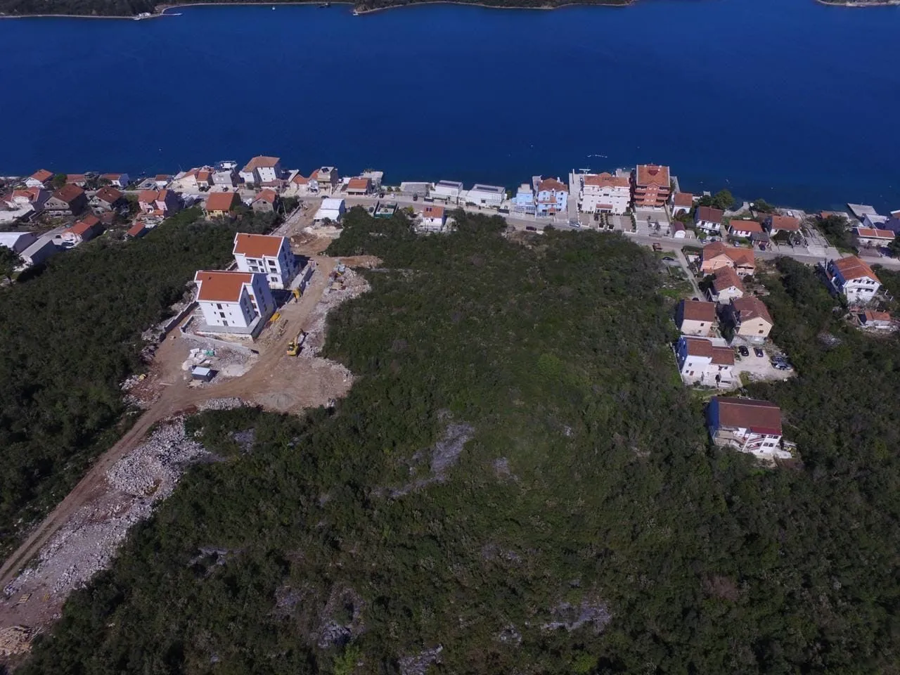 Pogled iz vazduha na priobalno naselje i objekte u izgradnji blizu mora.