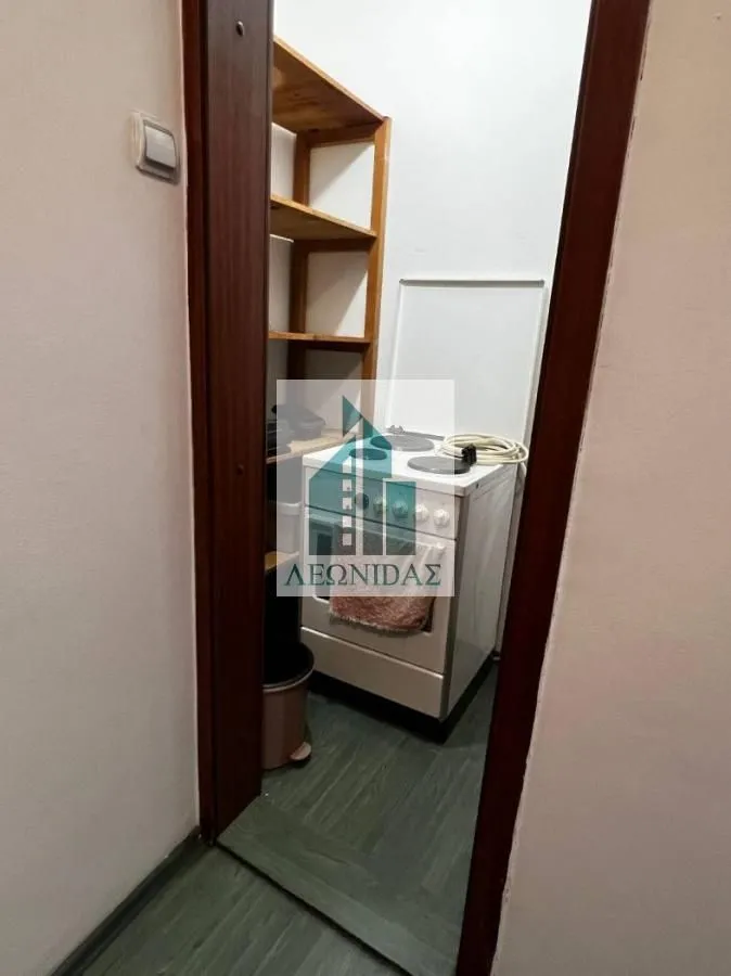 Small kitchen with a stove and wooden shelves.