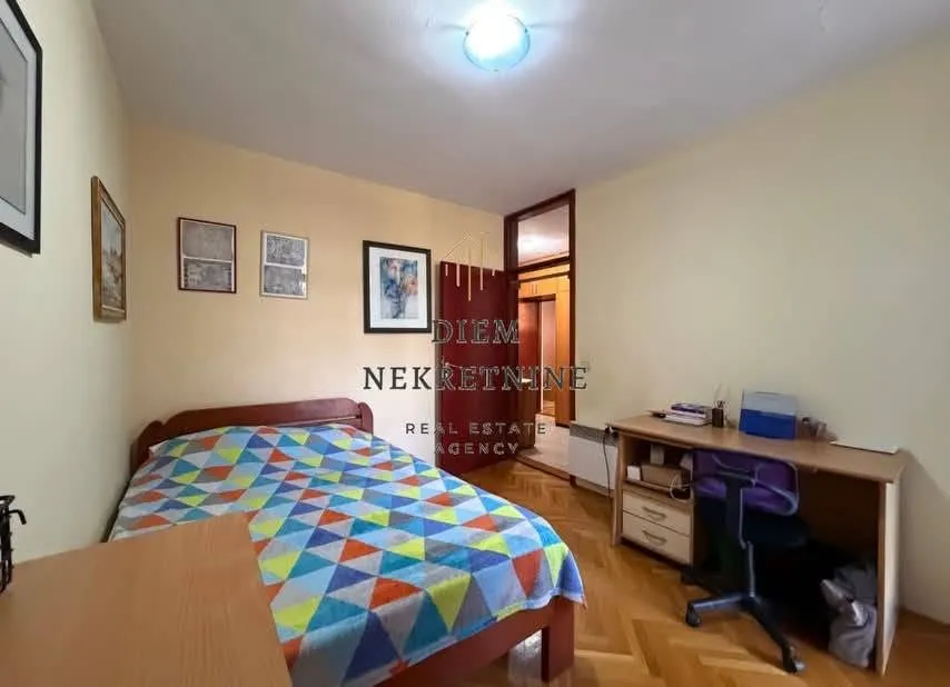 Namještena spavaća soba sa krevetom i radnim stolom.