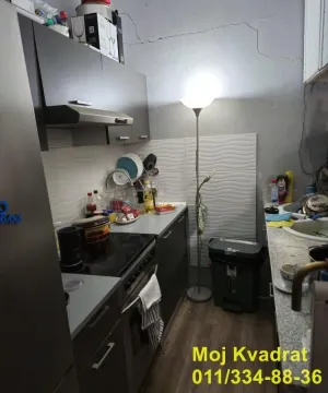 Manja kuhinja sa tamnim elementima i radnim površinama sa obe strane. - image 12
