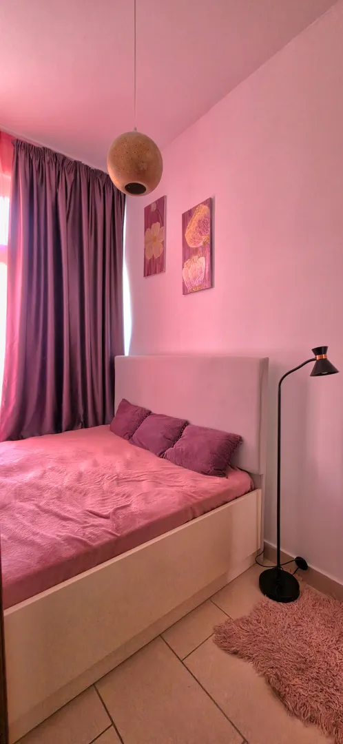 Furnished bedroom with a double bed in pink tones.