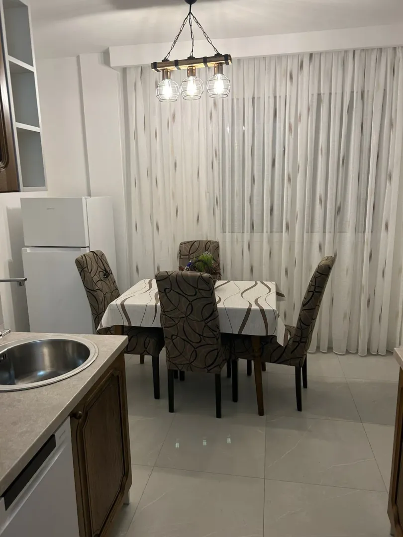 Dining table with chairs next to kitchen counters and a refrigerator.