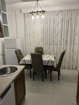 Dining table with chairs next to kitchen counters and a refrigerator. - image 4