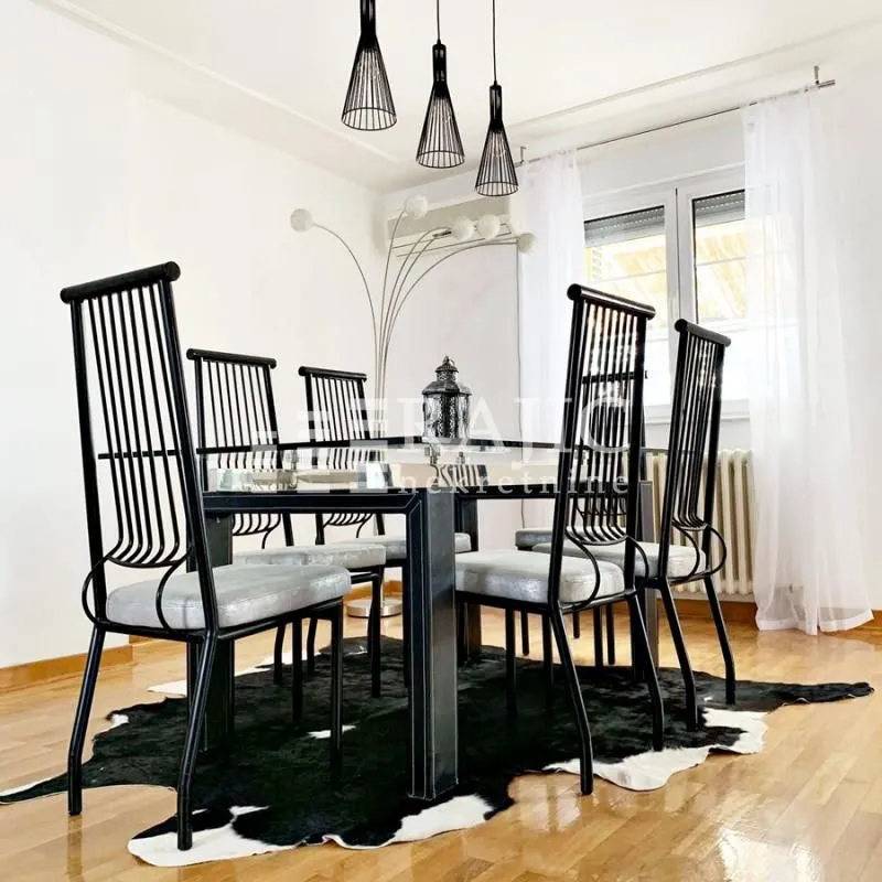 Dining room with a black table, chairs, and a faux-hide rug.