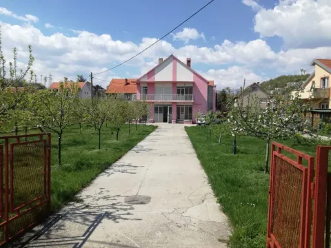 Dvospratna kuća sa roze fasadom, prostranim dvorištem i betonskom stazom. - image 6