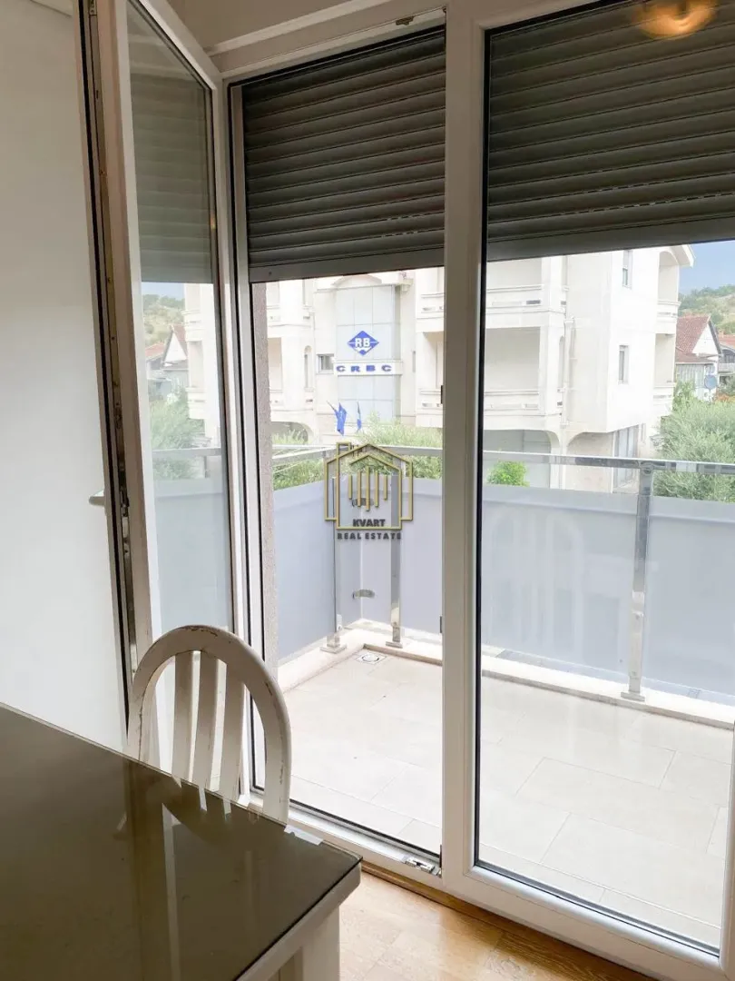 View through the balcony door onto the terrace and surrounding buildings.