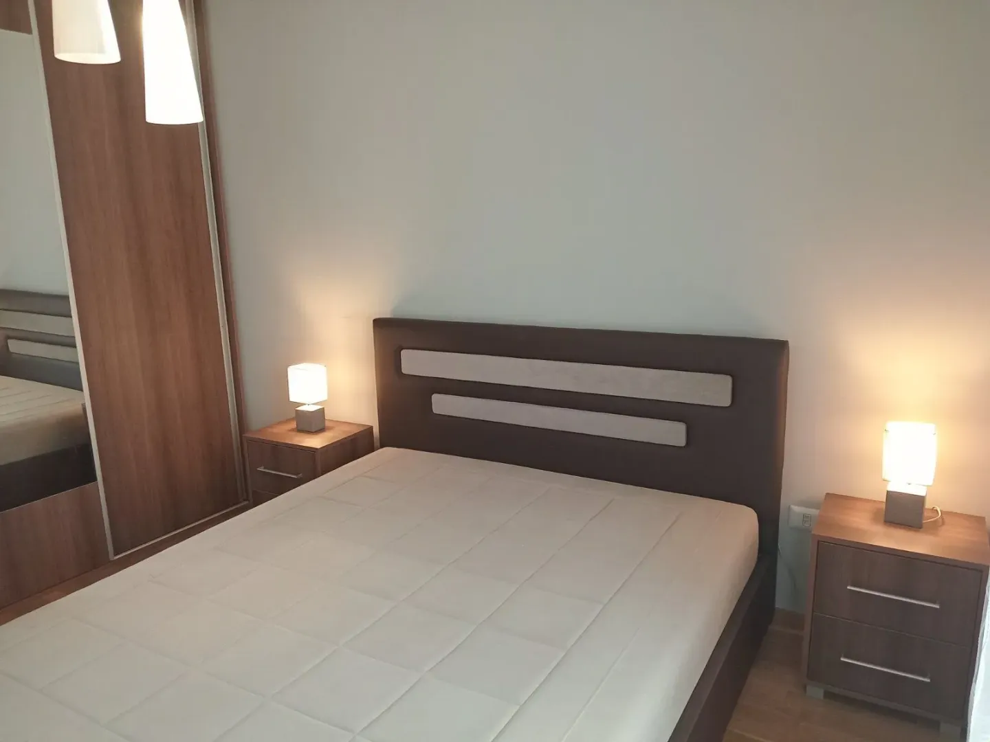 Spavaća soba sa bračnim krevetom, noćnim stočićima i garderoberom.